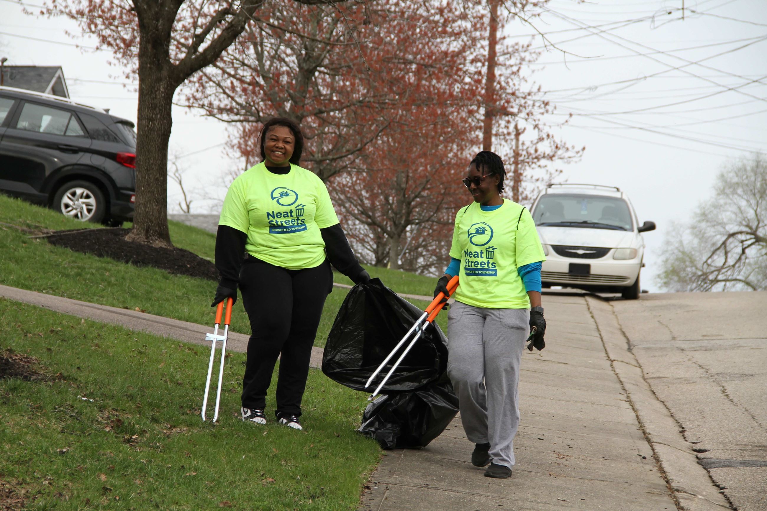 Two women pick up litter in West College Hill